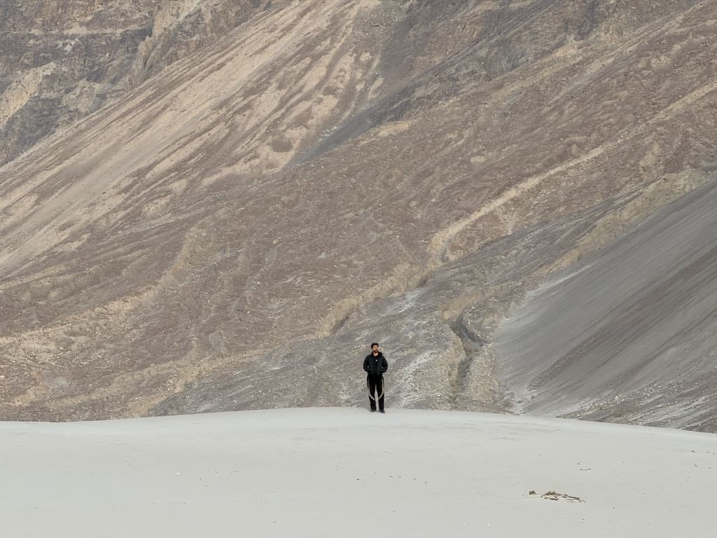 Mohtasham standing alone in front of a mountain slope