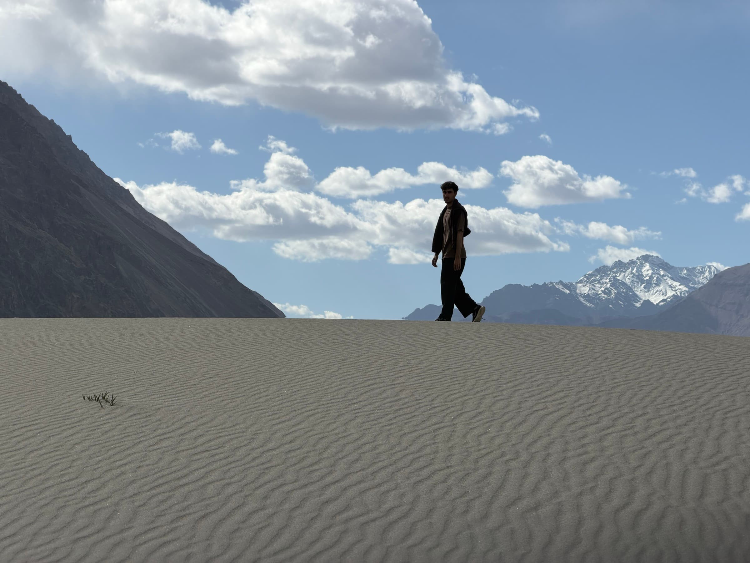 Mohtasham walking across sand beneath a blue mountain sky